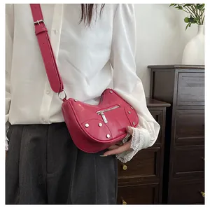 Detail of fuchsia dumpling bag featuring silver rivets and adjustable wide shoulder strap