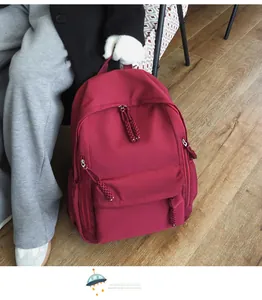 Detail view of burgundy backpack with durable nylon fabric and woven knot zipper pullers