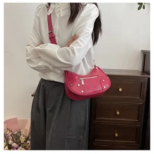 Detail of rose pink crescent bag with silver rivets and metal zipper on adjustable strap