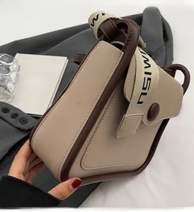 Dettaglio borsa a tracolla geometrica beige con bordo marrone e tracolla in tela