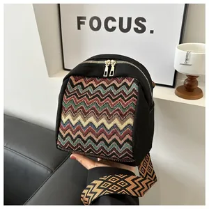 Detail of colorful wavy pattern textile and gold zippers on a black crossbody bag