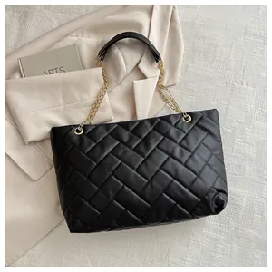 Detailed view of the black quilted tote bag with golden metal chain handles