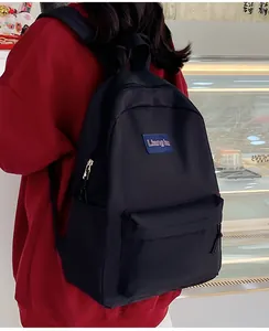 Detail eines schwarzen Nylon-Rucksacks mit blauem Logo-Patch und großer Fronttasche