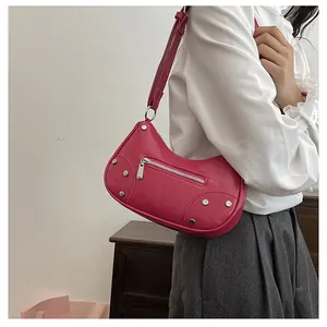 Detail of fuchsia dumpling bag featuring silver rivets and metal zipper on textured leather