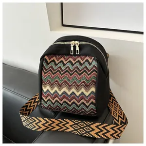 Detail of bohemian colorful zigzag strap and bright gold zippers on a black canvas bag