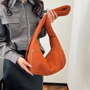 Detail of orange corduroy hobo bag showing ribbed texture and soft crescent shape