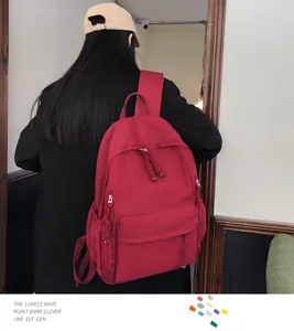 Detail view of durable red nylon backpack with zipper pulls and side pockets on model