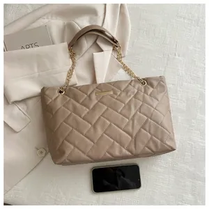 Detail of quilted tote bag with golden chain and smartphone for size comparison