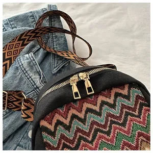 Detail of bohemian canvas crossbody bag with colorful zigzag weaving and golden zippers