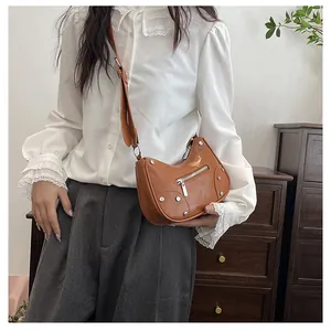 Detail of vintage brown crescent bag featuring silver studs and wide shoulder strap
