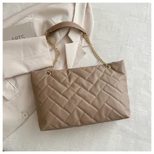 Detail of mocha quilted tote bag with large diamond pattern and gold chain strap