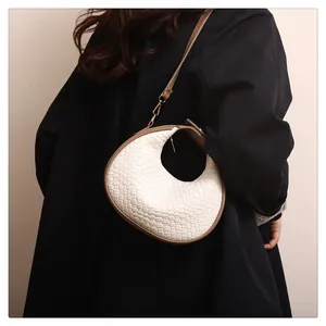 Détail du sac croissant tissé avec texture blanche et lanières en cuir marron