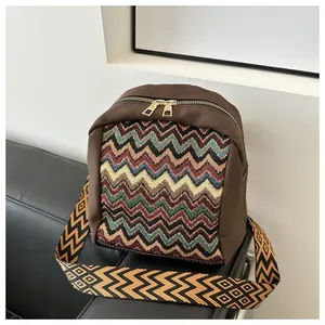 Close-up of ethnic style canvas bag with colorful wave knit pattern on a leather sofa