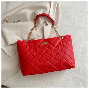 Close-up of red quilted tote bag with gold chain strap and textured leather finish