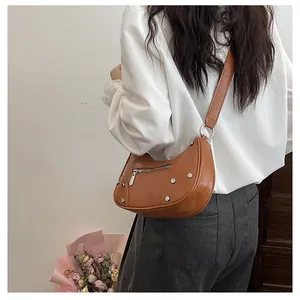 Detail of vintage rivets and smooth brown synthetic leather on crescent bag