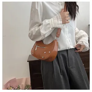 Close-up of a brown hobo bag with silver rivets and studs on a female model