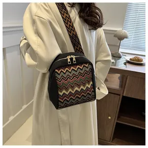 Detail view of ethnic woven patterns and gold metal zippers on a black crossbody bag