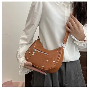 Close-up of vintage brown hobo bag with silver studs and metal ring strap detail