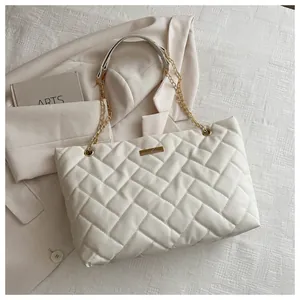 Detail of cream quilted tote bag with golden chain strap and textured woven pattern