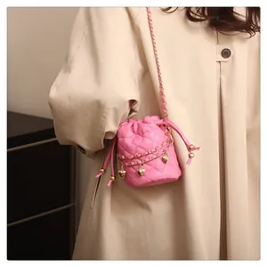 Rosa gesteppte Mini-Beuteltasche mit goldenen Herzanhängern und Kettenriemen am Model