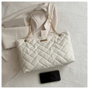 Flat lay of beige quilted tote bag with gold chain strap and stylish accessories