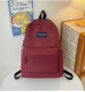 Detail eines burgunderroten minimalistischen Rucksacks mit Logo-Patch auf Tisch