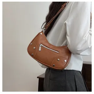 Close-up of vintage brown dumpling bag with silver studs and adjustable shoulder strap