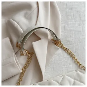 Close-up of beige quilted tote bag showing premium metal chain strap and stitching detail