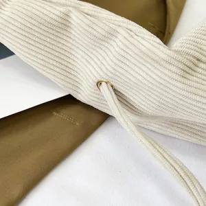 Close-up of white corduroy fabric texture with drawstring and gold metal eyelet details