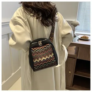Detail of colorful geometric jacquard pattern on black canvas crossbody bag with strap