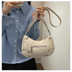 Detailed view of beige vintage dumpling bag with silver rivets and textured finish