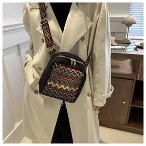 Close-up of ethnic crossbody bag with colorful wavy patterns and wide woven strap