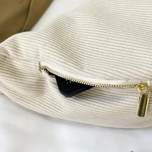 Macro shot of off-white corduroy shoulder bag showing side zipper and storage detail