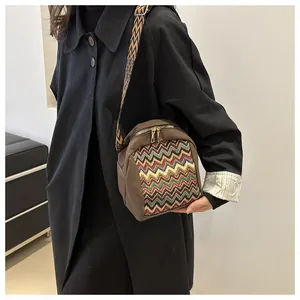 Close-up of ethnic crossbody bag with chevron weave and adjustable wide strap on model