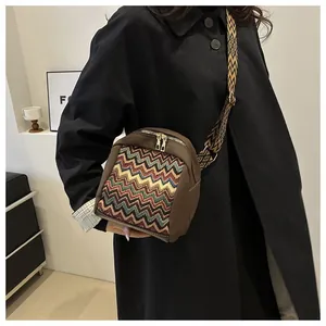 Detail of bohemian woven panel and adjustable jacquard strap on brown crossbody bag