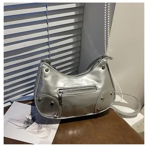 Close-up of silver rivet hardware and zipper pocket on a metallic PU crescent bag