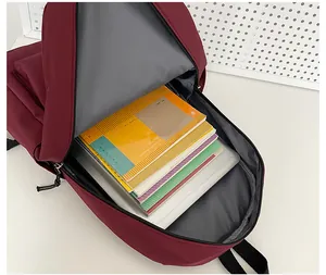 Details des großen Hauptfachs im dunkelroten Nylon-Rucksack mit Büchern gefüllt