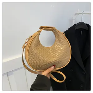 Detail showing the woven leather texture and rounded handle of the beige hobo bag