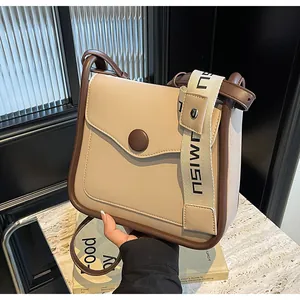 Dettaglio borsa beige con finiture marroni, fibbia rotonda e doppie tracolle intrecciate