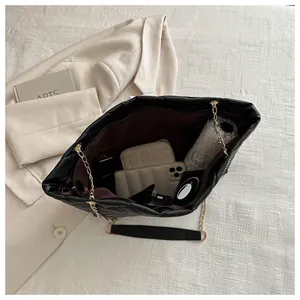 Interior view of black quilted tote bag showing large capacity for umbrella and phone