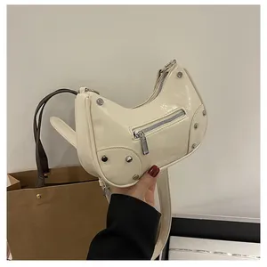 Detailed view of cream hobo bag with glossy wrinkled leather and silver metal rivets