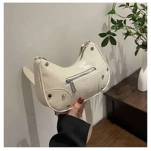 Detail of cream pleated leather dumpling bag with silver metal studs and zipper pockets