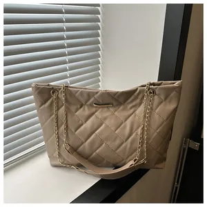 Detail of khaki quilted tote bag with golden metal trim and chain strap