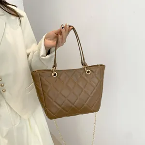 Sac fourre-tout matelassé marron avec chaîne dorée porté par un mannequin en blanc