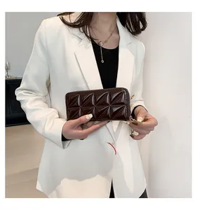 Détail d'un portefeuille en cuir verni marron avec surpiqûres pyramide et zip doré