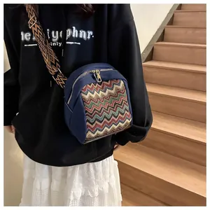 Close-up of navy canvas crossbody bag with colorful zigzag panel and woven strap