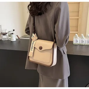 Detail of apricot crossbody bag featuring a contrast strap and decorative round buckle