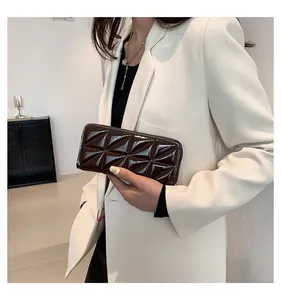 Détail du sac à main marron café en cuir verni avec surpiqûres triangulaires géométriques