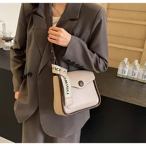 Detail shot of a minimalist cream crossbody bag with brown trim on a fashion model