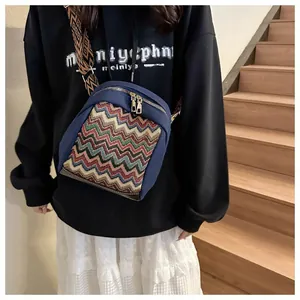 Detail view of ethnic style crossbody bag with colorful wave patterns and golden zippers